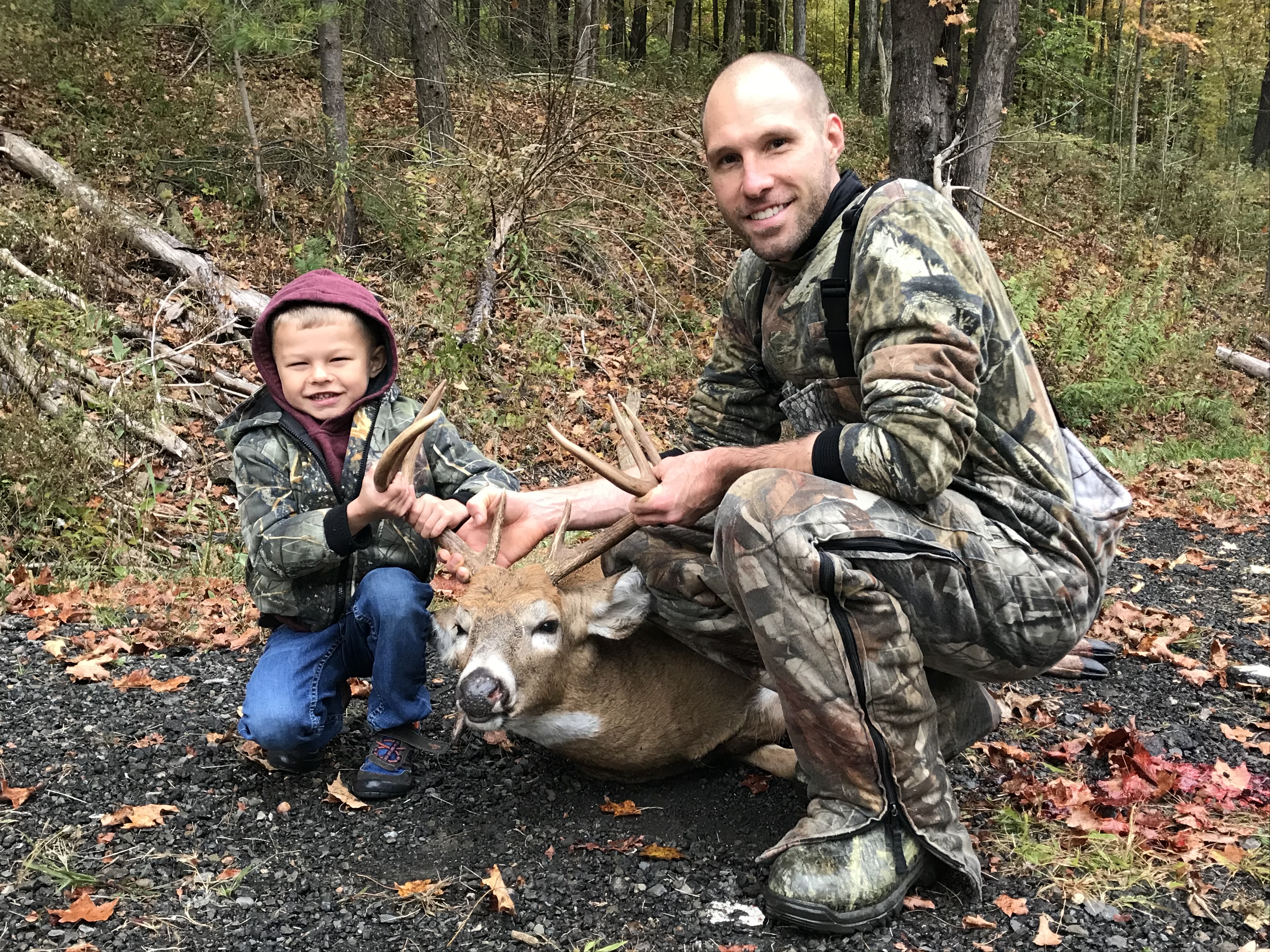 Jordan and a young Parker with a whitetail buck in the fall woods